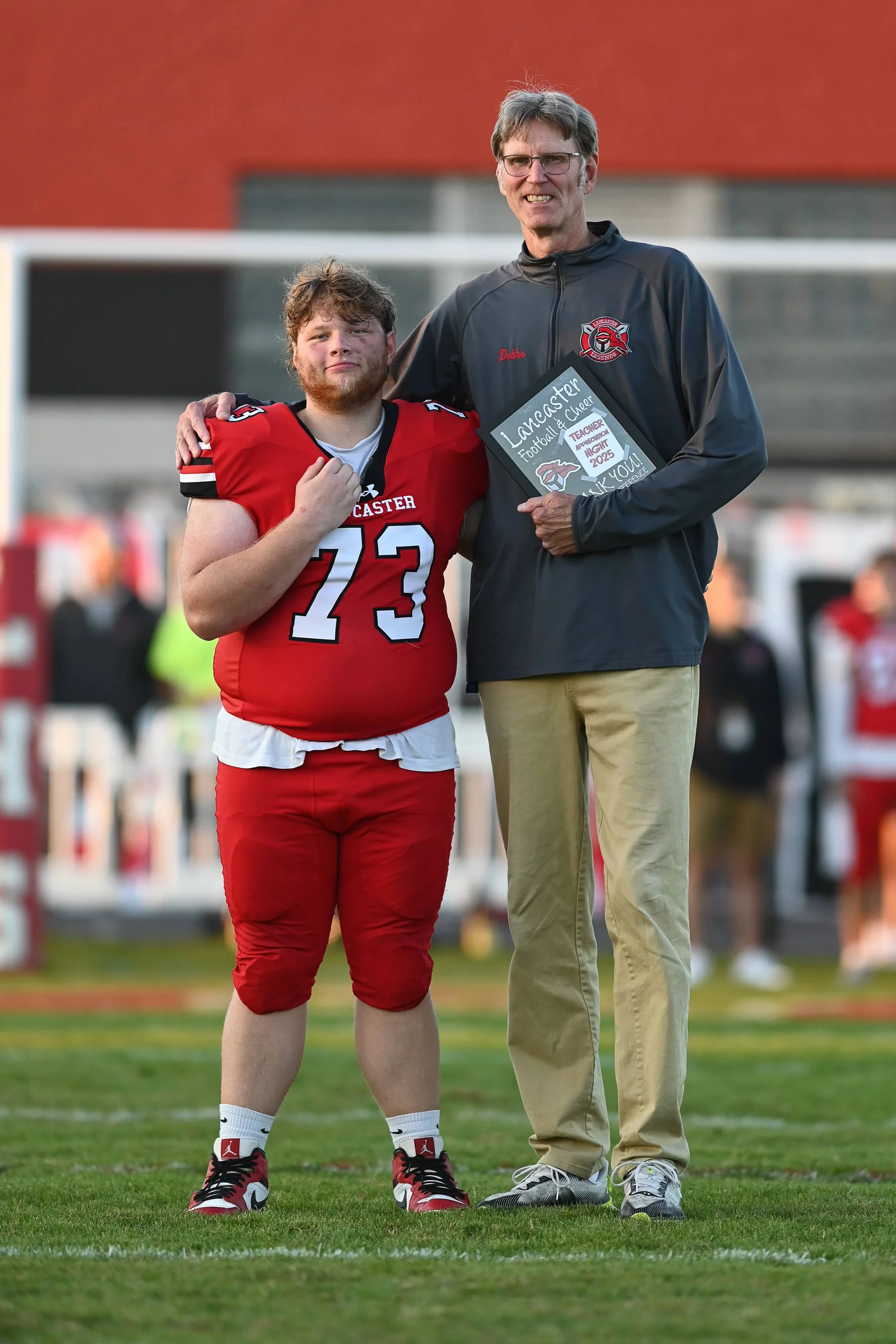 Ethan standing on the field with the teacher he chose
